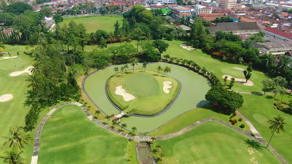Golf course with palm trees, artificial pond and island, aerial view