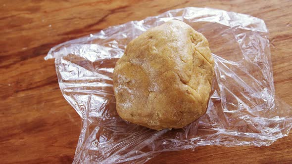 Dough placed over plastic wrap on a wooden table