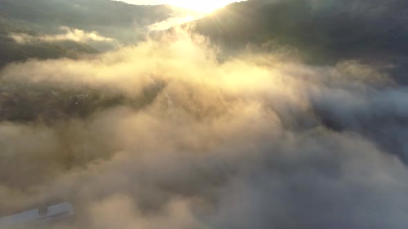 Flying Through Beautiful Sunny Cloudscape in the Mountains at Sunrise. Aerial View of Above Mountain