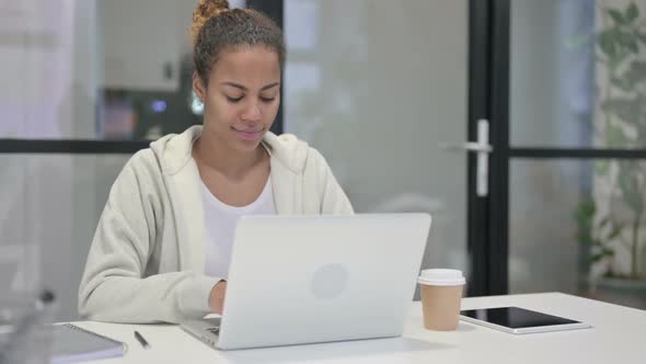 African Woman Showing Thumbs Down Sign While Using Laptop in Office