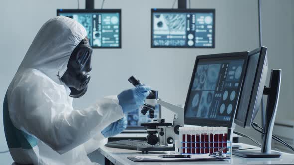 Scientist in protection suit and masks working in research lab using laboratory equipment.