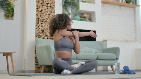 Young African Woman Doing Stretches on Yoga Mat at Home