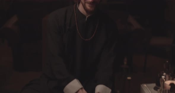 Shot of a Man Picking Up a Wooden Bowl Filled with Tea Smiling at the Camera