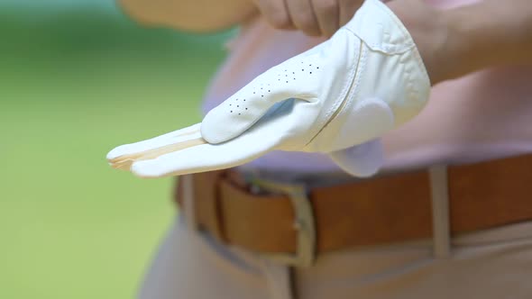 Close-Up Professional Female Golf Player Wearing and Adjusting Leather Glove