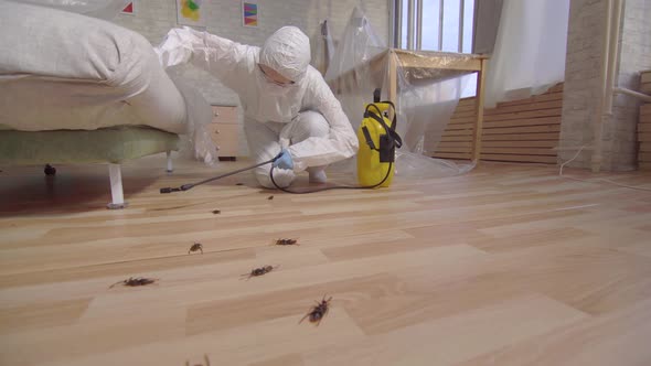 Pest Control Worker with Sprayer Standing at Home and Under the Couch