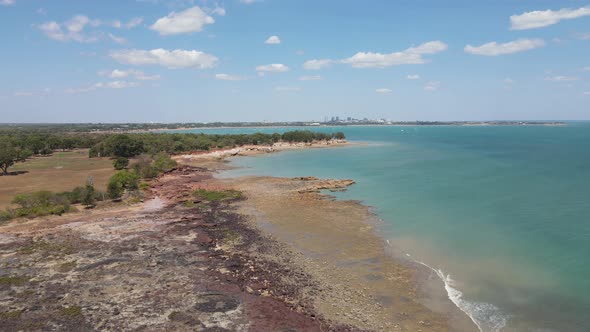 Slow Moving Aerial drone shot of East Point Reserve and Darwin Skyline, With Blue water and Green bu