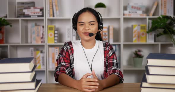 Happy female student in headphones and glasses talking at camera