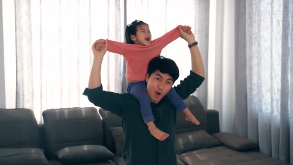 Little Girl Sitting On Her Fathers Shoulders At Home