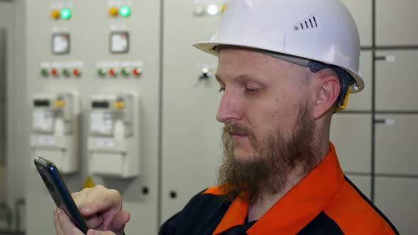 Closeup of a Bearded Man in a White Hard Hat at Work in Heavy Industry