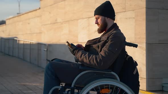 Disabled Man in Wheelchair Using Phone During Morning Outing in City