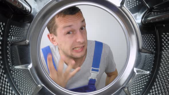 home appliance repairman sticks his head in drum of washing machine and screams