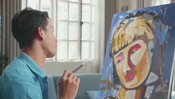 Asian Artist Man In Wheelchair Holding Paintbrush Thinking And Painting A Girl On The Canvas