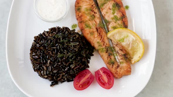 Dish with Fish and Black Rice on a White Plate