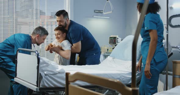 Male Nurse and Doctor Lifting Patient Into His Bed