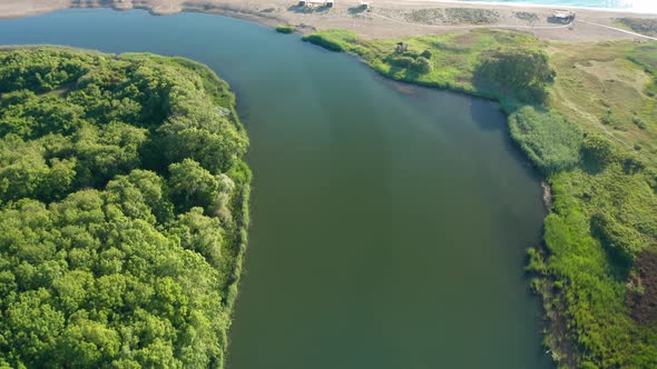 Drone flight over river, a wild sandy beach and sea