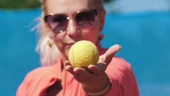 Female Tennis Coach Showing the Ball Then Hitting It with a Racket