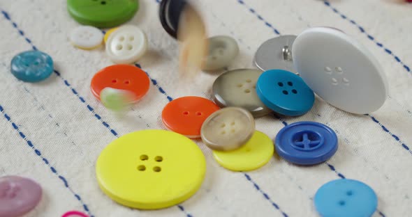 Colorful Buttons Falling on Striped Fabric Closeup