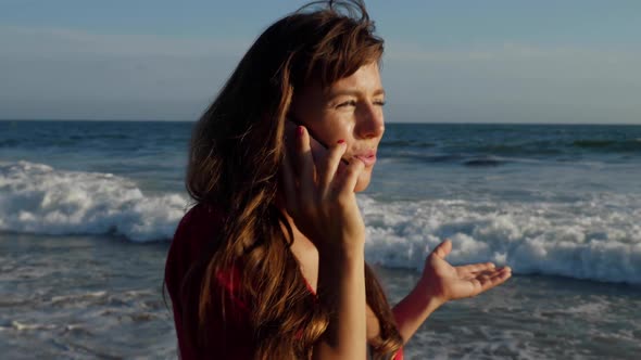 Attractive woman walking along the beach while talking on her phone