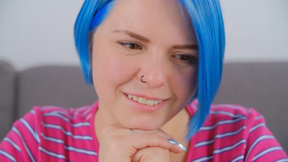 Video portrait of beautiful girl with colored blue hair looking in laptop with cheerful smile