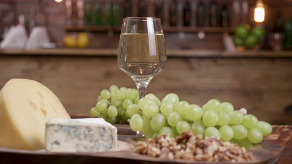 A Glass of White Wine with Grapes and a Variety of Cheeses