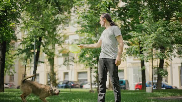 A Handsome Man Playing with His Dogs in a Park