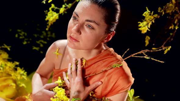 Stunning Woman is Playing with Yellow Flowers on Shore of Shallow River in Night