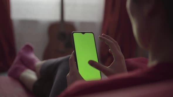 Back View of Woman Holding Chroma Key Green Screen Smartphone