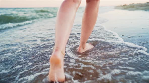 Legs of Girl Walking Barefoot on Wet Sandy Island Beach. Beautiful Feet of Young Woman Near Sea on