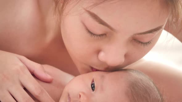 Beautiful young asian mother with her newborn baby on bed at home