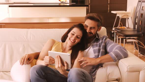 Couple relaxing on sofa and using digital tablet