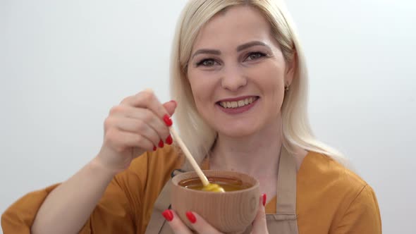 Smiling Young Woman with Bowl of Honey on White Background