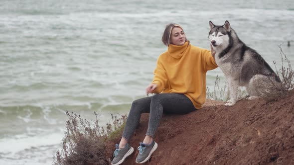 Young Beautiful Female Walking with Siberian Husky Dog on the Beach
