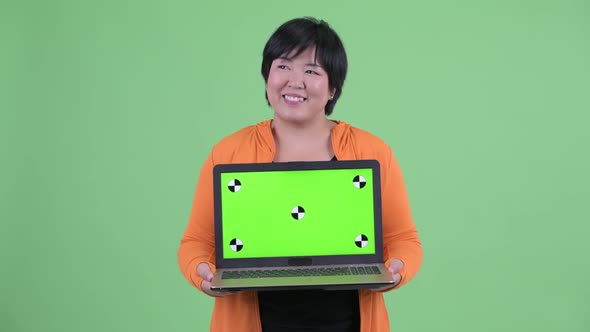 Happy Young Overweight Asian Woman Thinking While Showing Laptop Ready for Gym