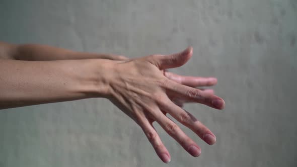 Female Hands Turn the Open Palms in Different Directions, Then Connect the Fingers. Gray Background