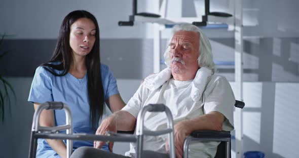 Female Physiotherapist Talking with Senior Patient About Walking Frame