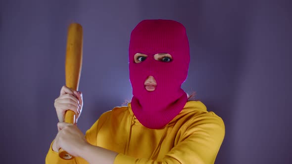 Young Woman in Pink Balaclava with Baseball Bat in Hands