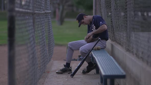 A baseball player resting on the bench.