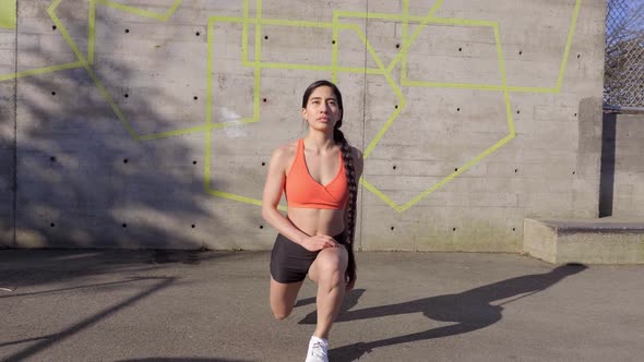 Young fit woman doing lunge exercise outdoors in sunshine