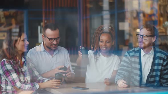 Happy Diverse Friends Sitting At Table In Coffee Shop And Talk