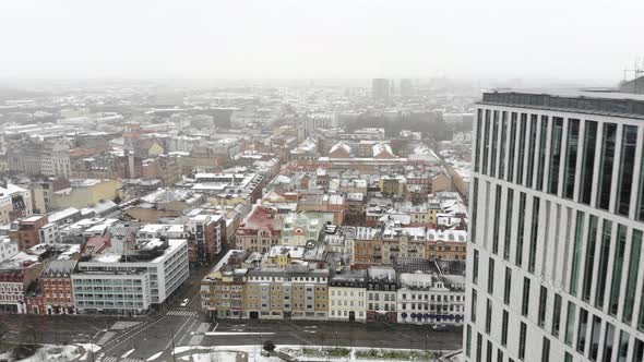 Drone flying straight forward over Malmö beside Clarion hotel while it is snowing