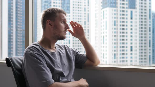 A Depressed Young Man with a Headache Sitting By the Window in His Office