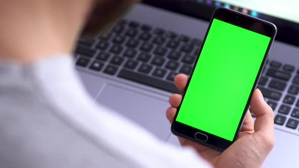 A Black Smartphone with Green Screen for Chroma Key Compositing Swipe Left the Hands of a Man