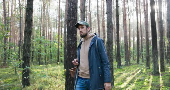 Young Man Mushroom Picker Walking in Unknown Forest Looking for Mushrooms Stands in Middle of Trees