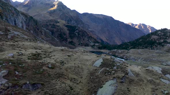 Lac d'Espingo mountain runoff lake in Haute-Garonne, Pyrénées, France behind a boulder hill, Aerial