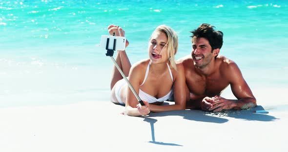 Couple lying on beach and taking a selfi from mobile phone