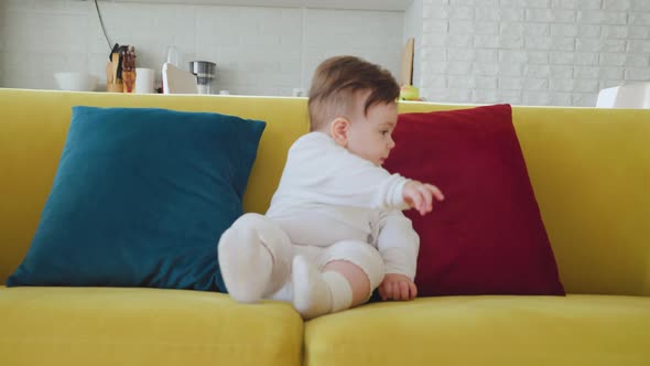 Cute Baby Sitting on Colorful Sofa in Living Room