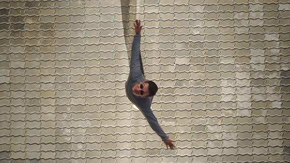 Top view Happy handsome man in sunglasses raises his hands up and spins with happiness