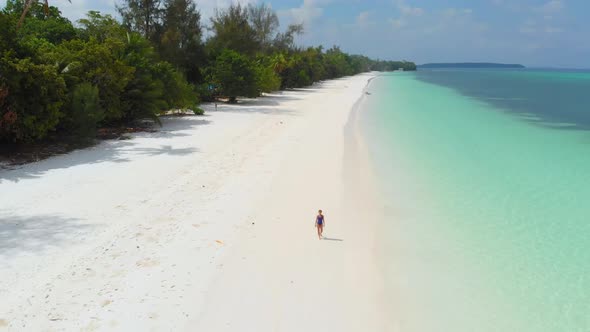 Aerial: Woman walking on white sand beach turquoise water tropical coastline Pas