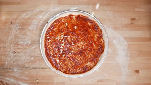 Top-shot Hand of talented chef finishing sprinkle mozzarella on a pizza dough