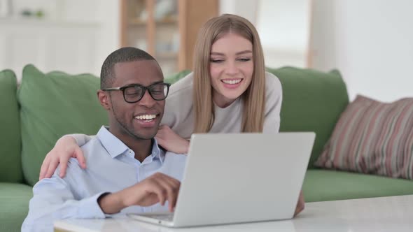 Mixed Race Couple Hugging While Doing Video Call on Laptop Home